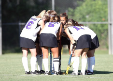 group of girls huddle on soccer field
