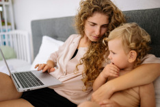 white mom with little boy sitting on bed