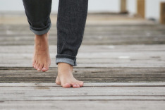 bare feet, jeans rolled up slightly, walking on wooden path
